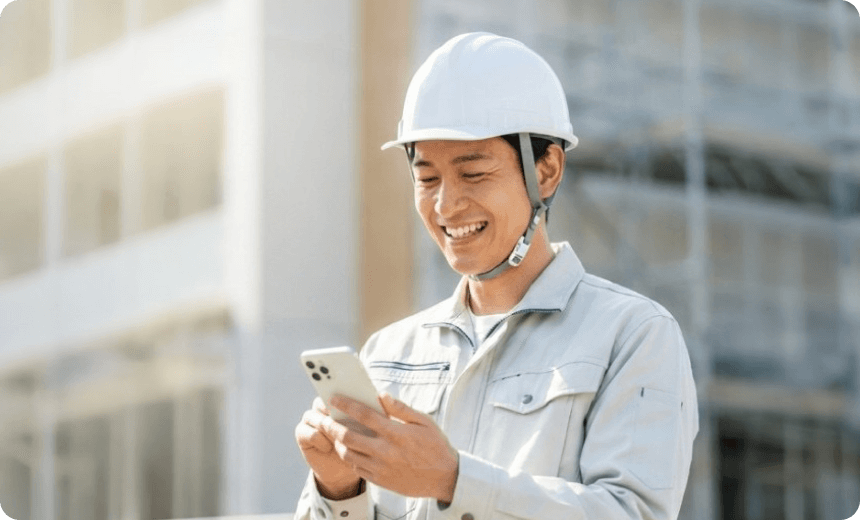 現場でスマホを使い相談する作業員